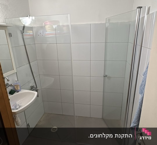 מקלחון עם דלתות זכוכית וכיור בחדר אמבטיה